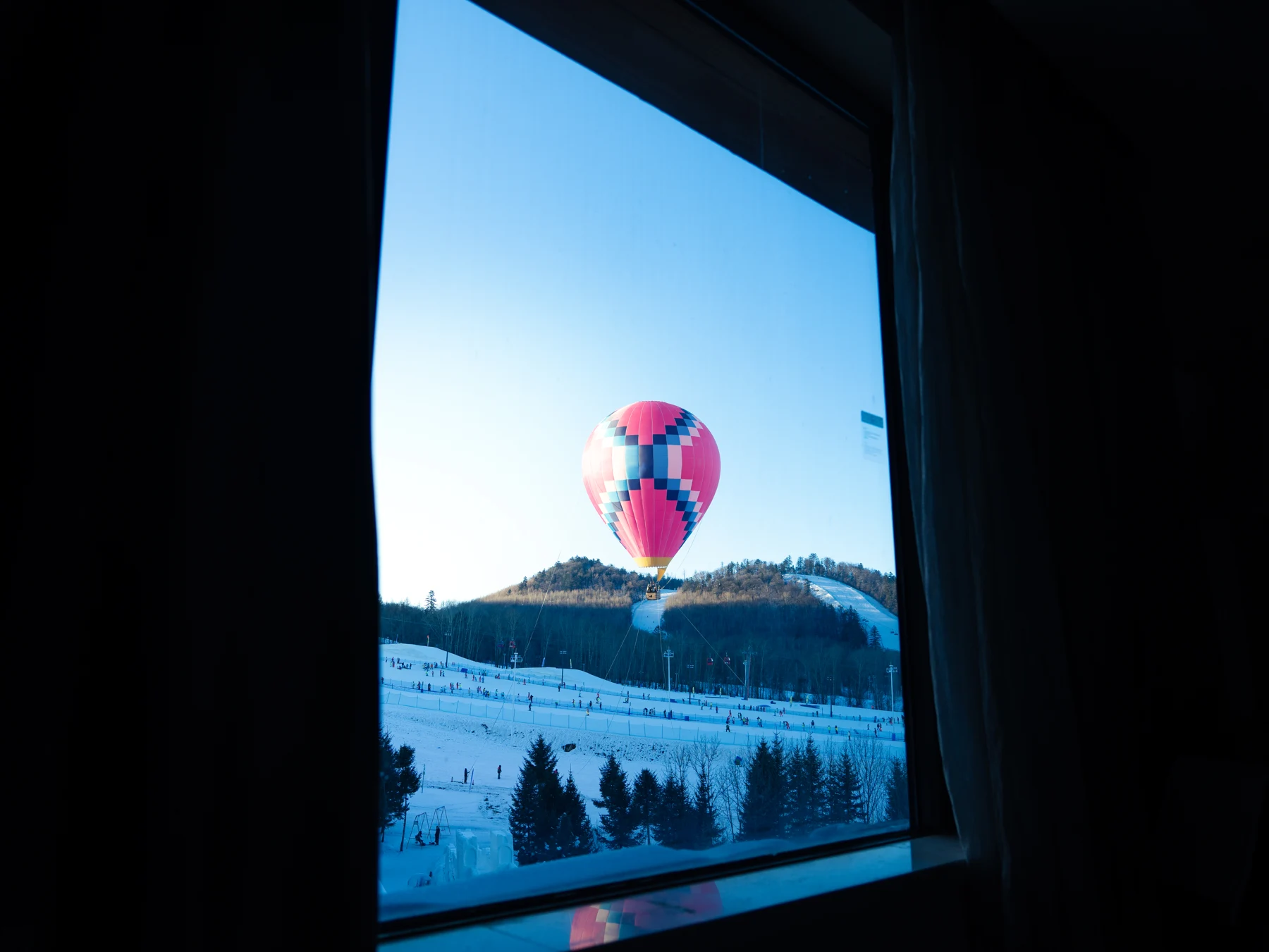 A hot-air balloon seen through a dark window.