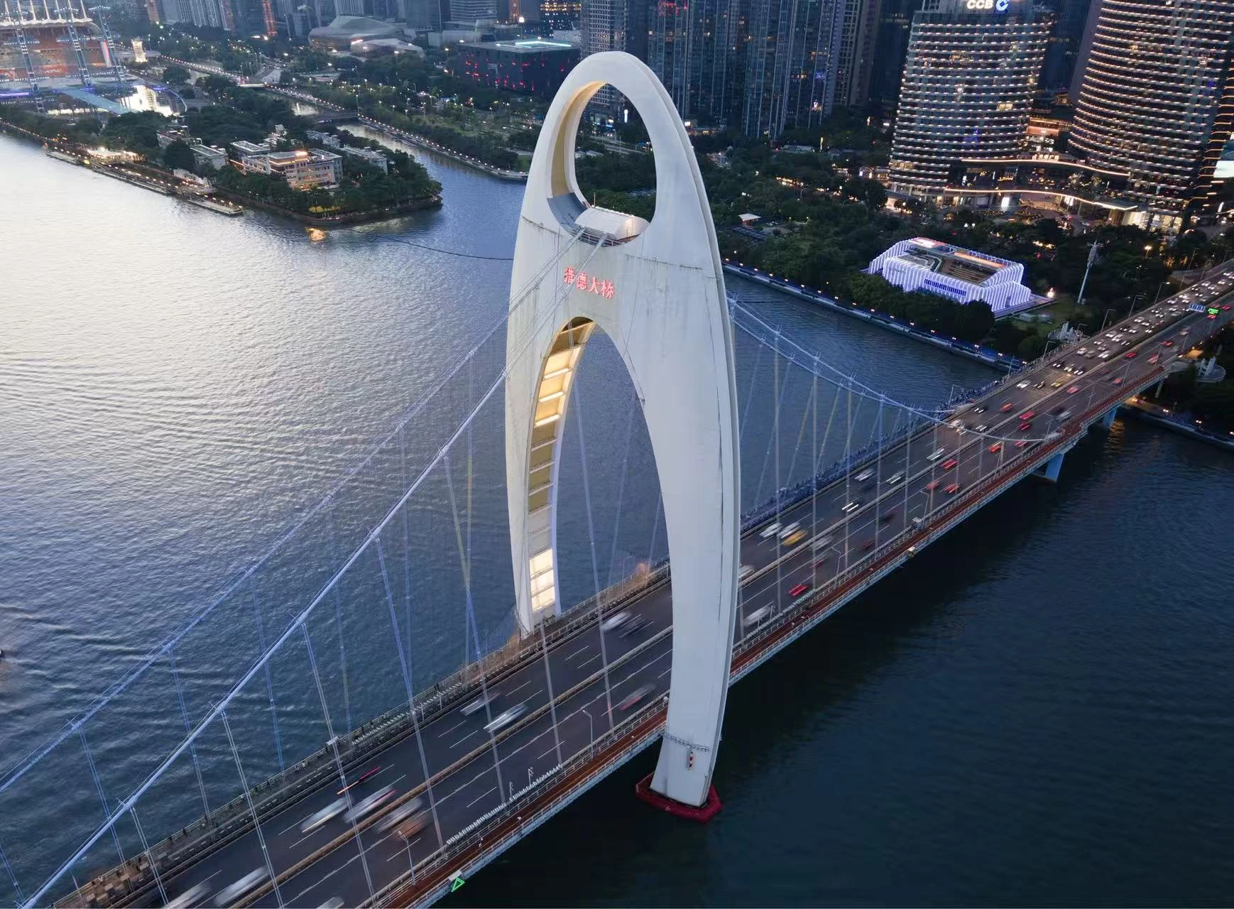 A white bridge arch over a river at dusk.