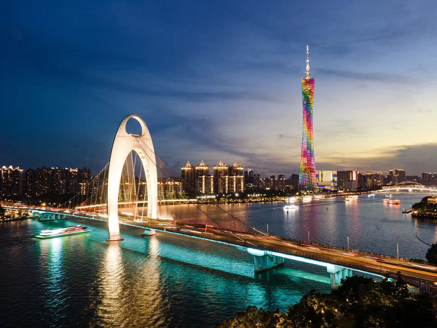 An illuminated bridge and tower reflected in a river.