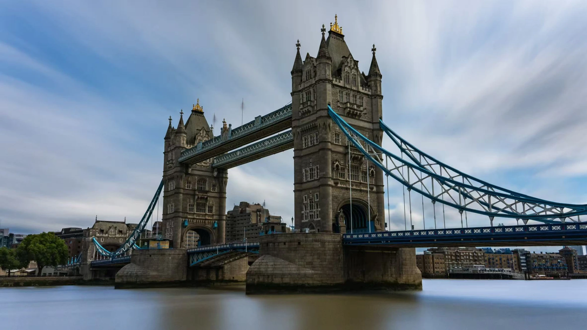 A stone suspension bridge beneath streaked clouds.